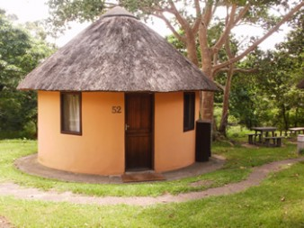 Traditional two-bed thatched rondavel surrounded by trees at Hilltop Camp in Hluhluwe Game Reserve