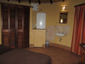 Two-bed rondavel bedroom with private washbasin and storage cupboards at Hilltop Camp